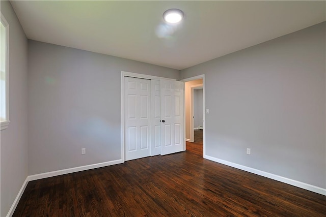 unfurnished bedroom with dark hardwood / wood-style flooring and a closet