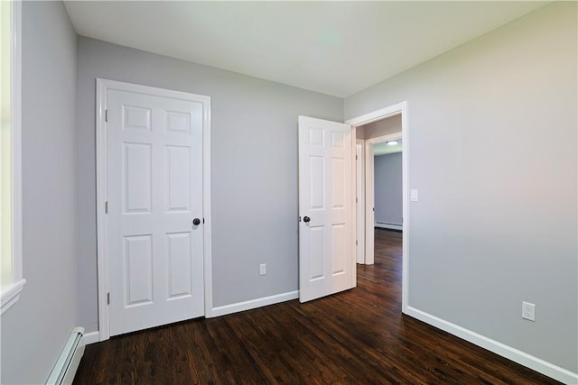 unfurnished bedroom featuring dark hardwood / wood-style flooring and a baseboard radiator