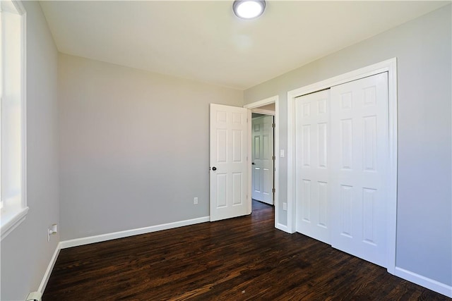 unfurnished bedroom featuring dark hardwood / wood-style flooring and a closet