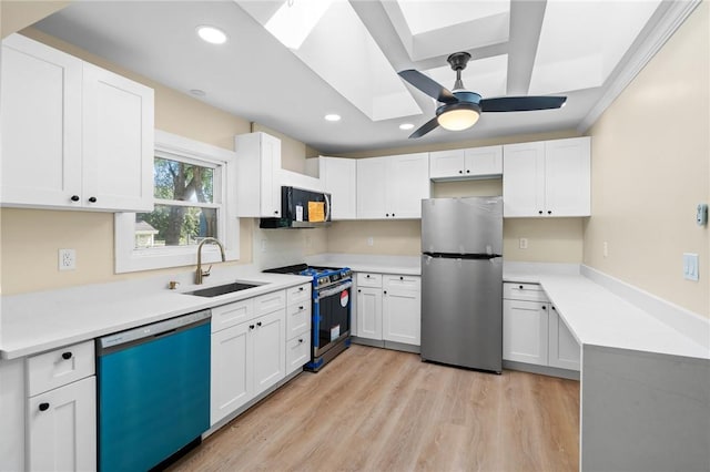 kitchen featuring sink, a skylight, light hardwood / wood-style flooring, appliances with stainless steel finishes, and white cabinetry