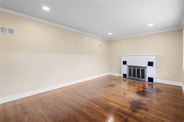 unfurnished living room featuring wood-type flooring, crown molding, and a brick fireplace