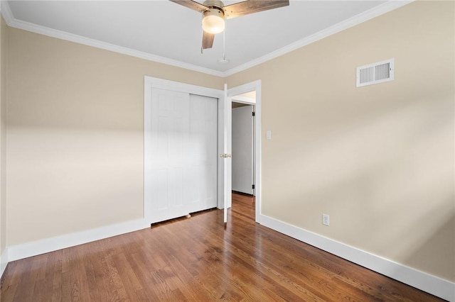 unfurnished bedroom with hardwood / wood-style flooring, ceiling fan, crown molding, and a closet