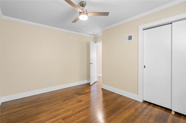 unfurnished bedroom with dark hardwood / wood-style flooring, a closet, crown molding, and ceiling fan