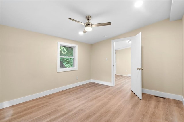 spare room with ceiling fan, lofted ceiling, and light wood-type flooring