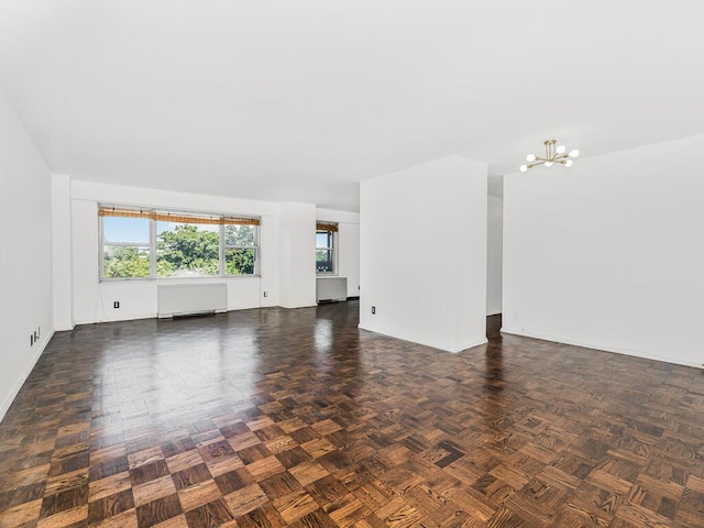 unfurnished living room featuring dark parquet flooring and an inviting chandelier