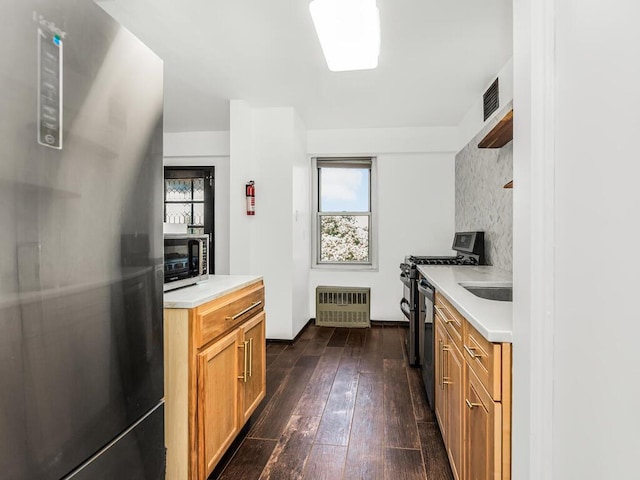 kitchen with dark hardwood / wood-style floors, appliances with stainless steel finishes, and heating unit