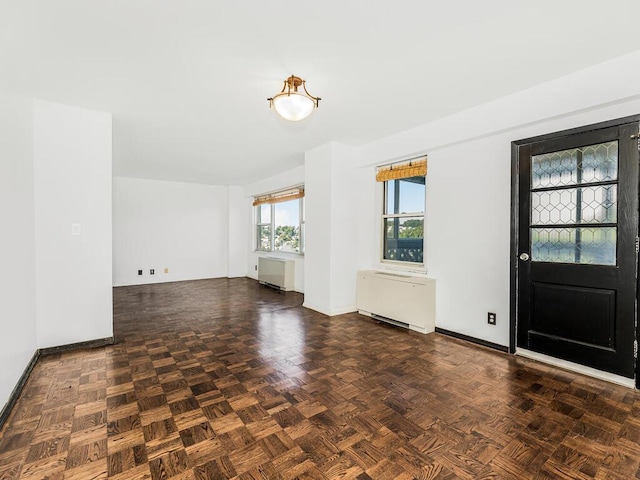 entrance foyer featuring dark parquet flooring and radiator heating unit