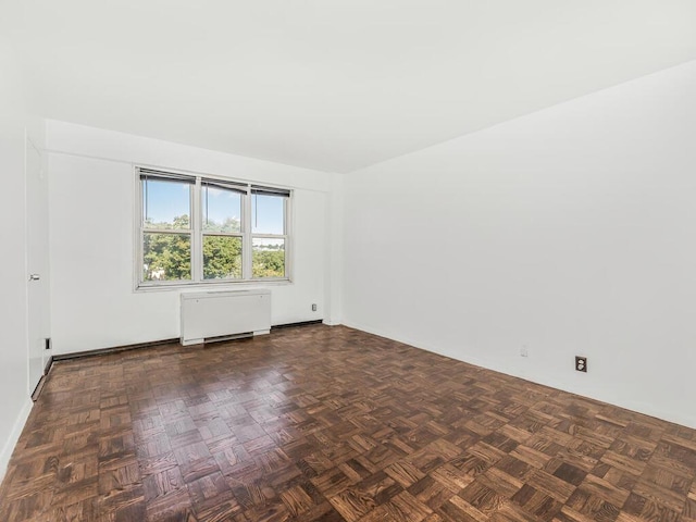 spare room with dark parquet flooring and radiator