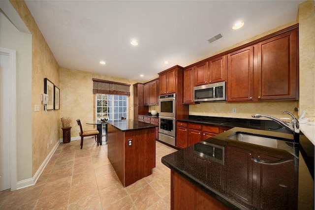 kitchen featuring a center island, stainless steel appliances, dark stone countertops, and sink