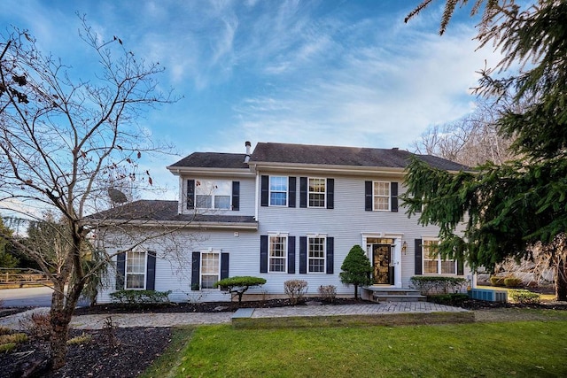 colonial home featuring central AC and a front lawn