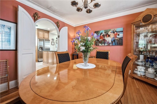 dining space featuring light hardwood / wood-style floors, crown molding, and a chandelier