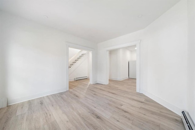 spare room featuring baseboard heating and light hardwood / wood-style flooring