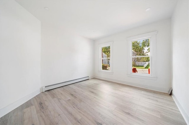 unfurnished room featuring a baseboard radiator and light hardwood / wood-style flooring