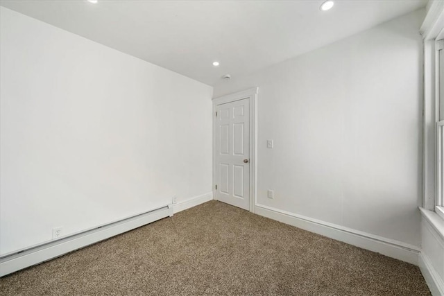 carpeted empty room with a baseboard heating unit