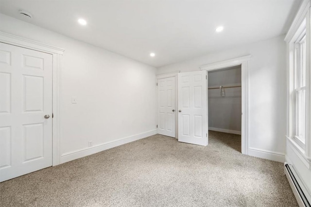 unfurnished bedroom with baseboard heating, multiple windows, and light colored carpet