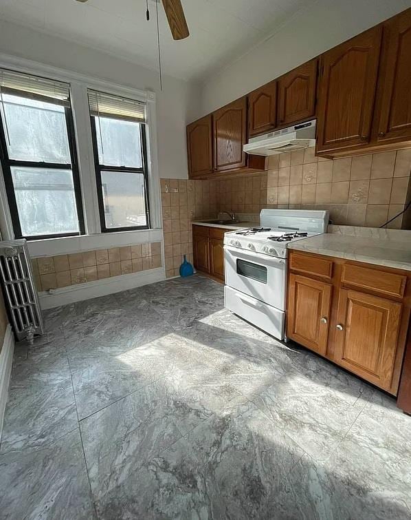 kitchen with tile counters, ceiling fan, decorative backsplash, and gas range gas stove