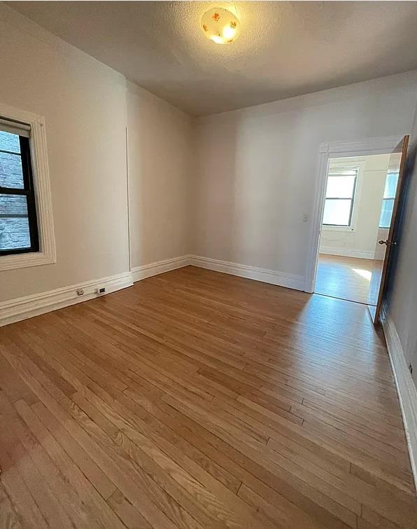 unfurnished room with a textured ceiling and light hardwood / wood-style floors