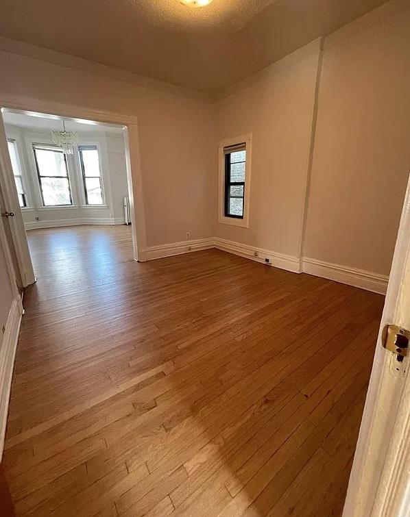 spare room featuring light hardwood / wood-style flooring, a textured ceiling, and a notable chandelier