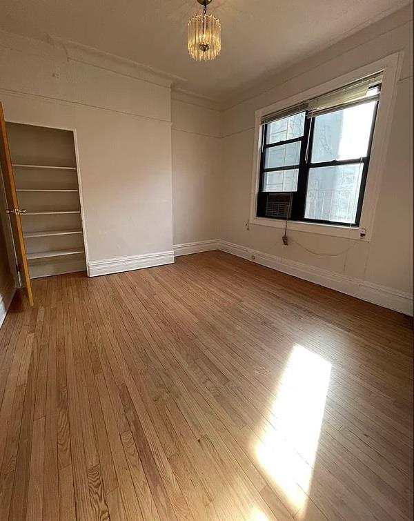 3216 31st Ave, Astoria, NY 11106 - spare room featuring light wood-style floors, baseboards, and a chandelier