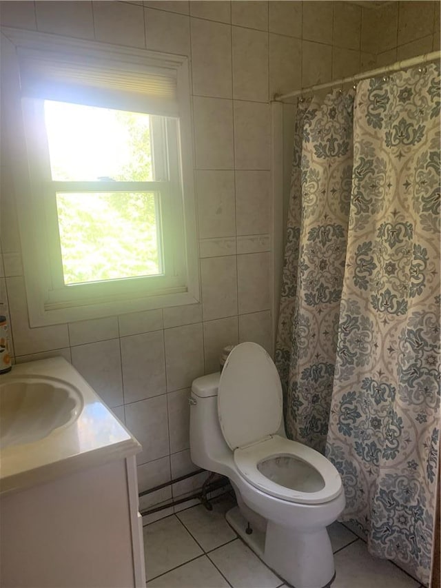 bathroom featuring walk in shower, tile patterned floors, toilet, vanity, and tile walls