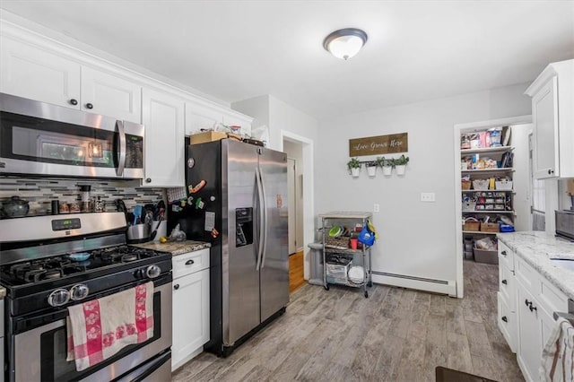 kitchen with light hardwood / wood-style floors, white cabinetry, a baseboard radiator, and appliances with stainless steel finishes