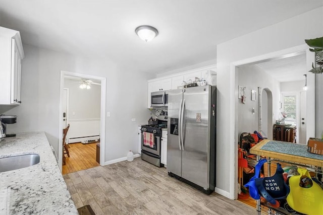 kitchen with light stone countertops, stainless steel appliances, ceiling fan, light hardwood / wood-style floors, and white cabinetry