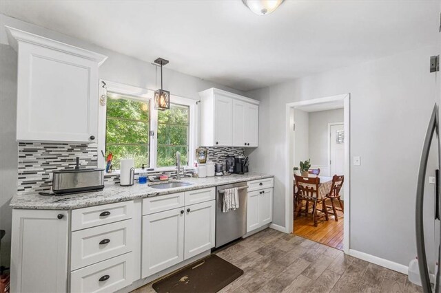 kitchen featuring sink, hanging light fixtures, stainless steel appliances, white cabinets, and light wood-type flooring