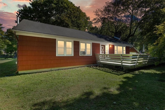 back house at dusk featuring a yard and a wooden deck