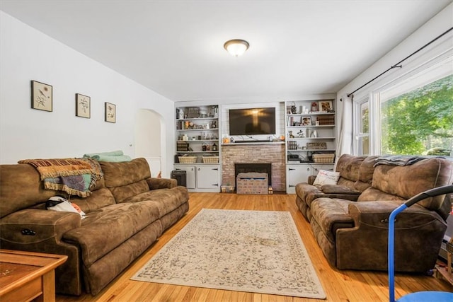 living room with a fireplace, wood-type flooring, and built in features