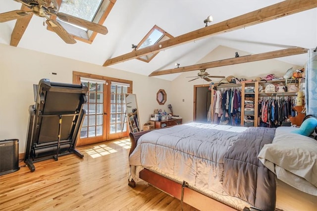 bedroom featuring a skylight, ceiling fan, high vaulted ceiling, light hardwood / wood-style flooring, and beamed ceiling