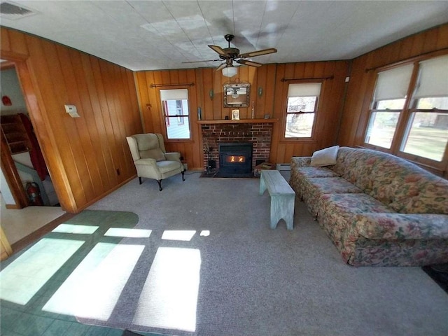 carpeted living room with a brick fireplace, ceiling fan, and wood walls