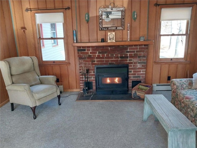 living room featuring carpet flooring, a baseboard radiator, a wood stove, and wood walls