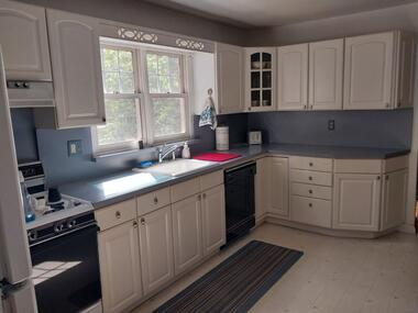 kitchen with sink, range hood, white cabinetry, and black appliances