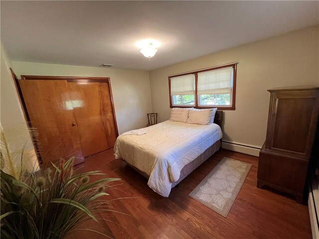 bedroom featuring baseboard heating, a closet, and dark hardwood / wood-style floors