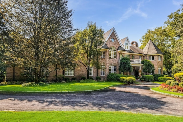 view of front of house with a front lawn and a balcony