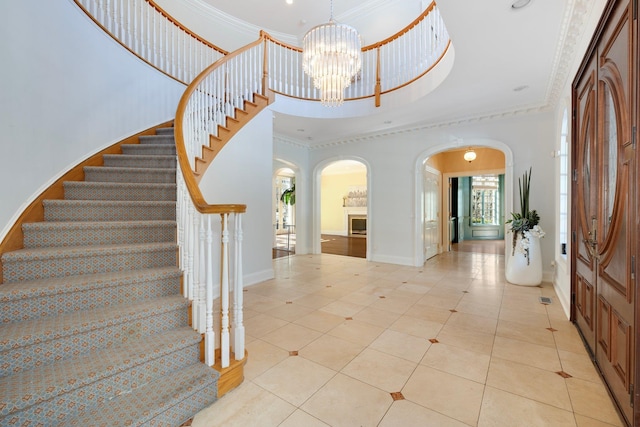 foyer with a towering ceiling, stairs, a chandelier, and crown molding