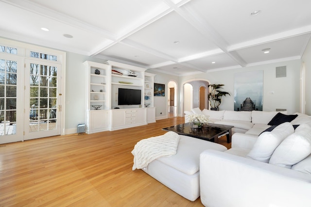 living room with arched walkways, coffered ceiling, visible vents, and light wood finished floors