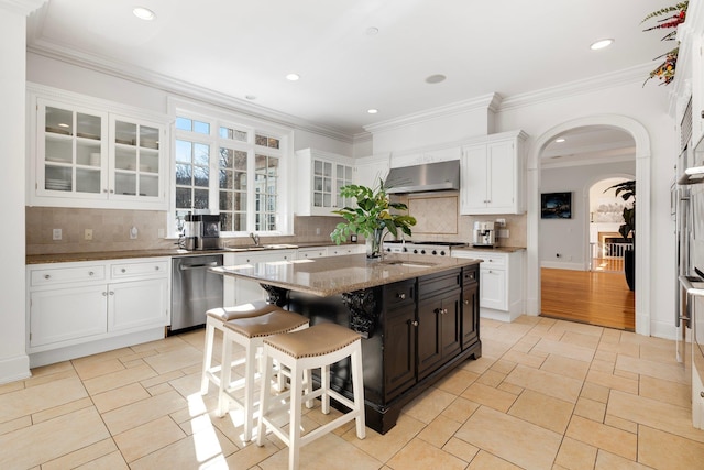 kitchen with white cabinetry, wall chimney exhaust hood, arched walkways, and stainless steel dishwasher