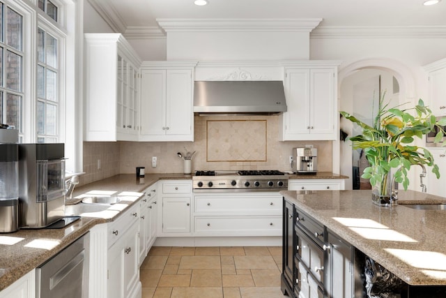 kitchen with stainless steel gas cooktop, ornamental molding, white cabinets, and range hood