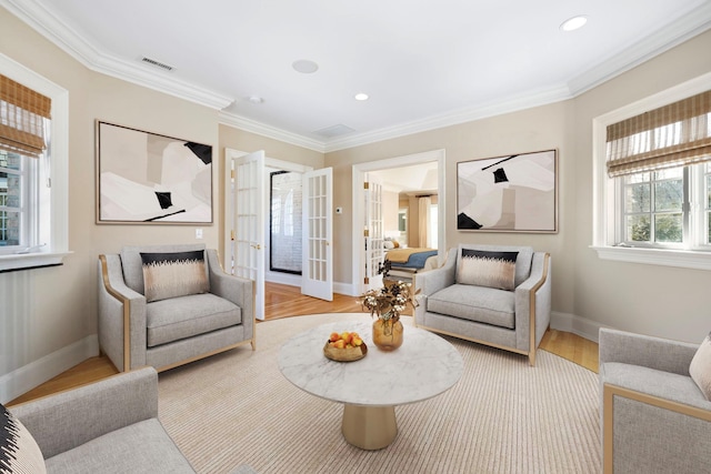 living room featuring light wood-style floors, baseboards, visible vents, and ornamental molding