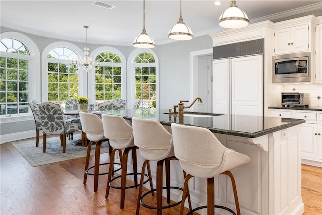 778 Sleepy Hollow Rd, Briarcliff Manor, NY 10510 - kitchen featuring built in appliances, plenty of natural light, an island with sink, decorative light fixtures, and crown molding