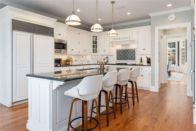 778 Sleepy Hollow Rd, Briarcliff Manor, NY 10510 - kitchen featuring built in appliances, light wood-style flooring, white cabinets, a kitchen breakfast bar, and ornamental molding