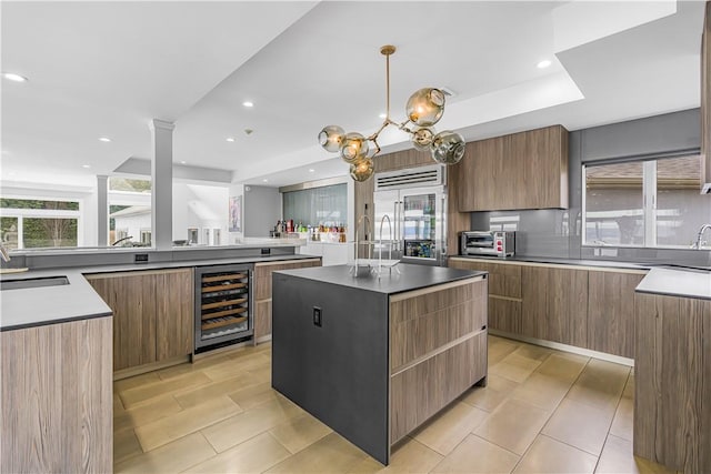 kitchen featuring beverage cooler, sink, decorative light fixtures, stainless steel built in fridge, and a center island