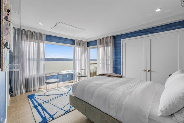 bedroom with a water view and light hardwood / wood-style flooring