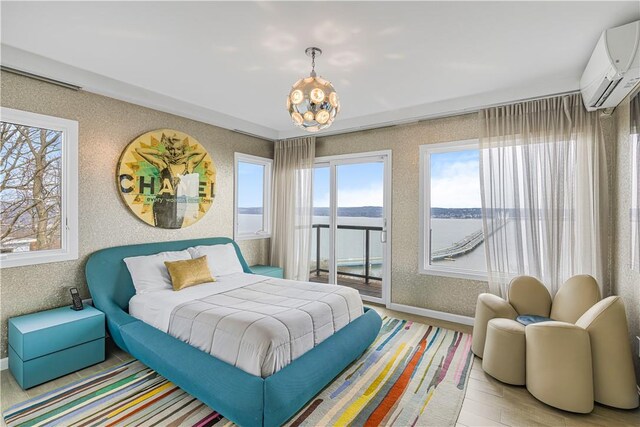 bedroom featuring a wall mounted air conditioner, a water view, light hardwood / wood-style floors, and a notable chandelier