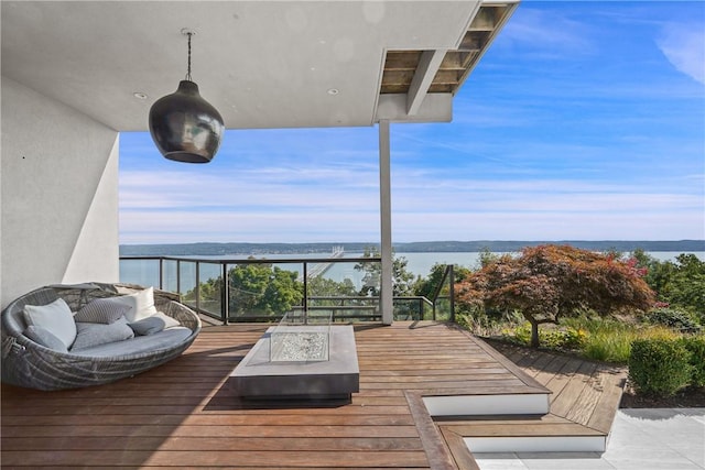 wooden terrace featuring a water view and an outdoor living space with a fire pit