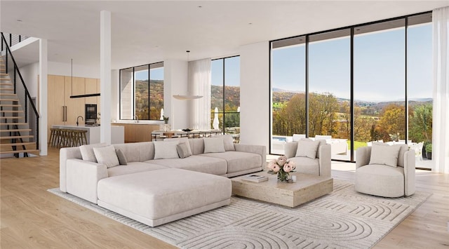 living area featuring light wood finished floors, floor to ceiling windows, and stairway