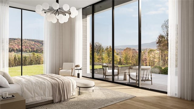 bedroom with a chandelier, access to outside, floor to ceiling windows, and light wood finished floors