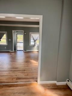 spare room with wood-type flooring and a baseboard heating unit