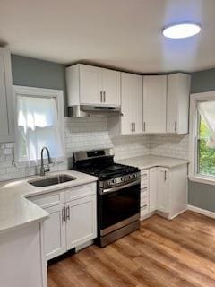 kitchen featuring white cabinets, decorative backsplash, sink, and stainless steel gas range